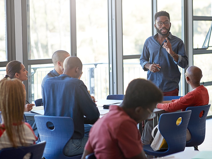 Man with glasses teaching a class of students