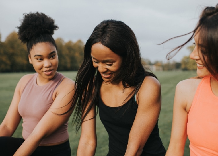 a group of women sitting together outside on the grass