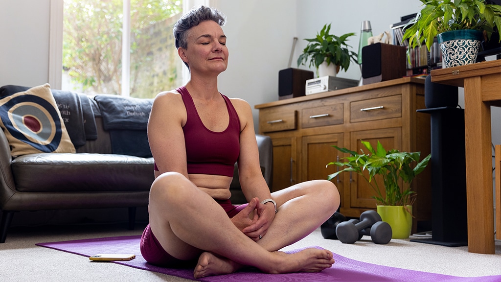 mature adult woman sitting with her legs crossed on an exercise mat