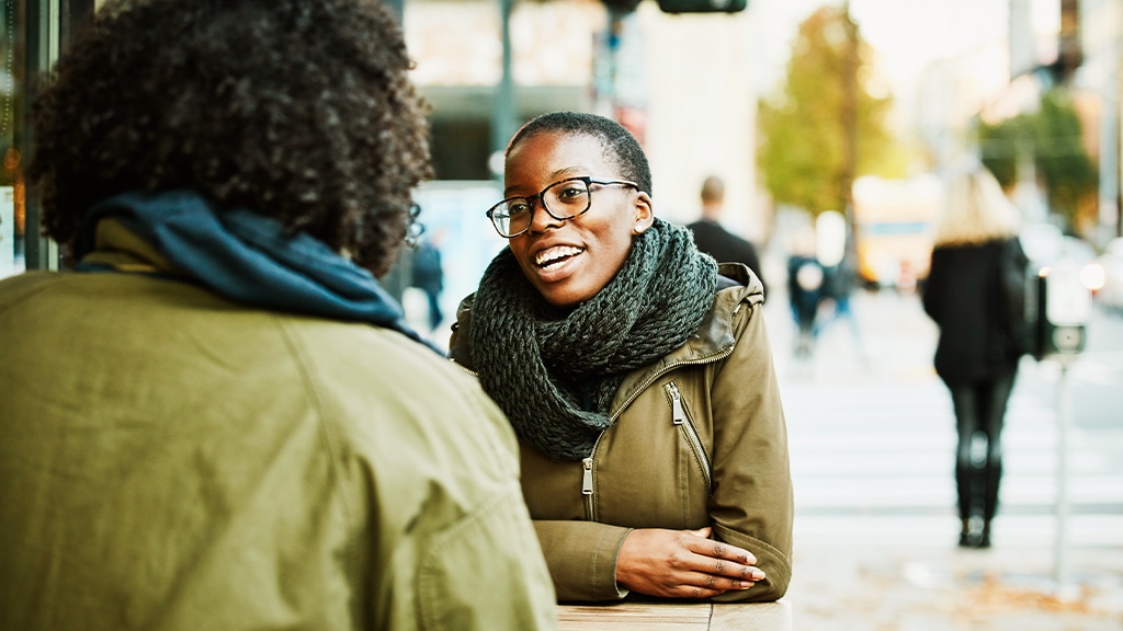 Two woman sitting together talking at a table outside a cafe