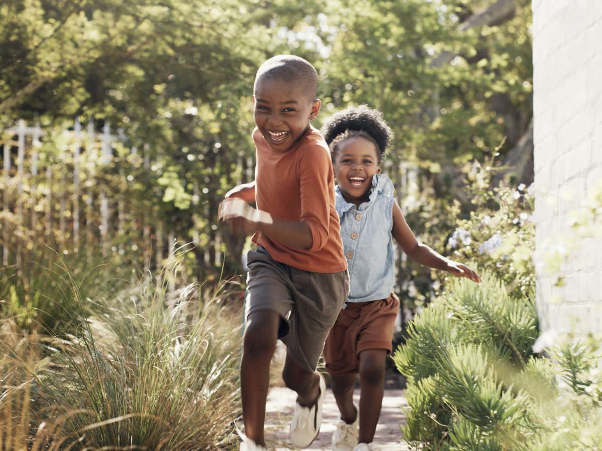 A brother and sister run along a path together.